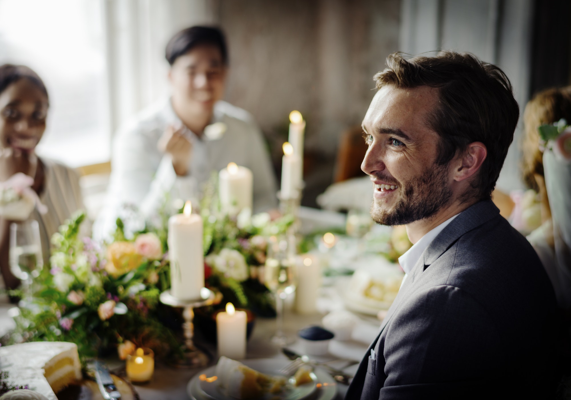 Man smiling at a formal dinner event with guests and candles on the table.