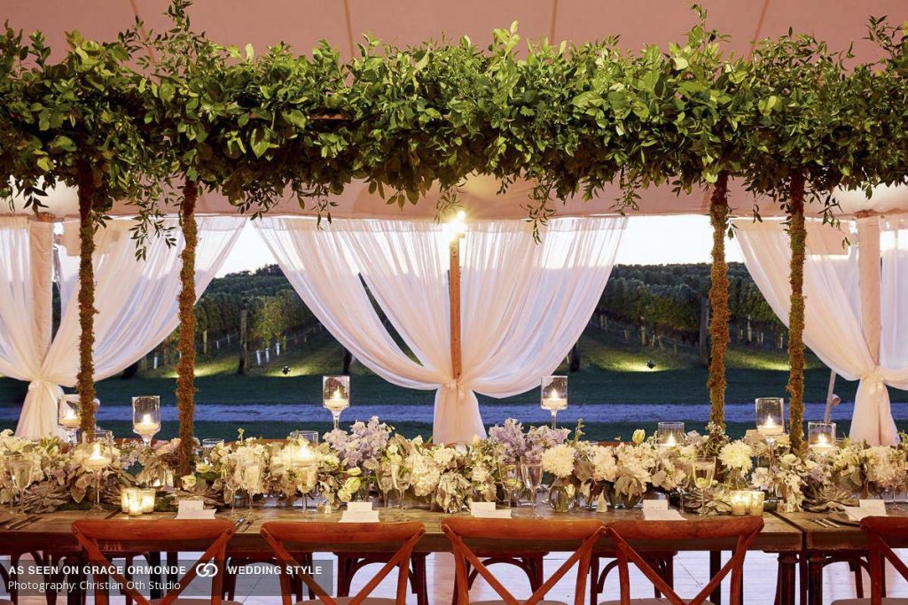 Elegant outdoor wedding reception table with floral arrangements and a view of rolling hills in the background.