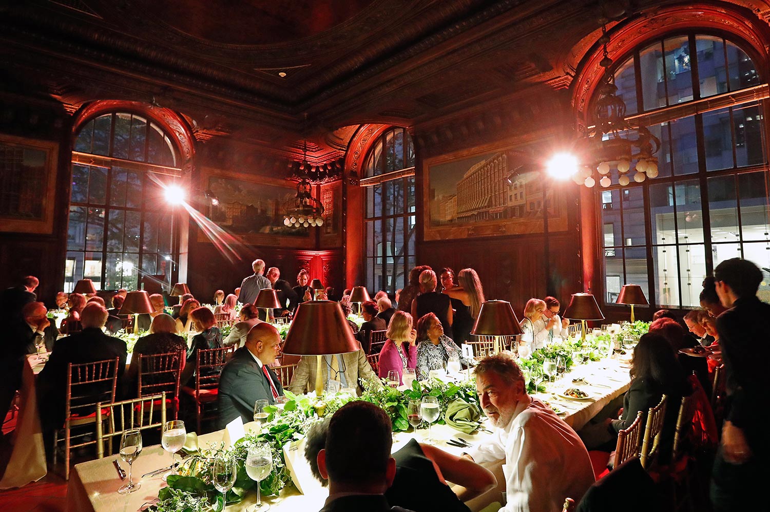 Formal dinner event in an elegant room with red ambient lighting.