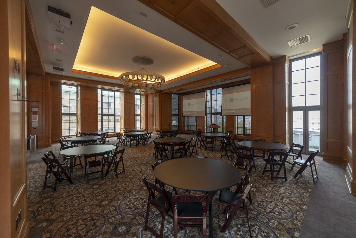 Spacious conference room with circular tables, wooden paneling, and large windows.