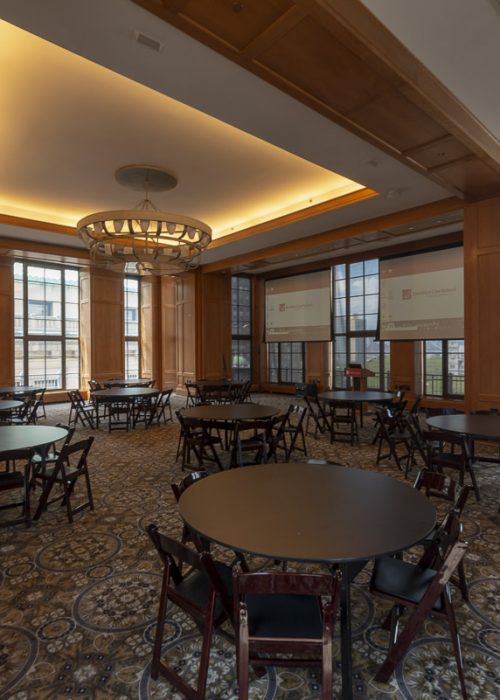 Spacious conference room with circular tables, wooden paneling, and large windows.